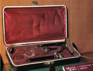 Set di strumenti medici d'epoca in una valigetta foderata di rosso, comprendente uno specchio per la testa, una lente d'ingrandimento e altri strumenti per l'esame disposti in compartimenti adeguati.